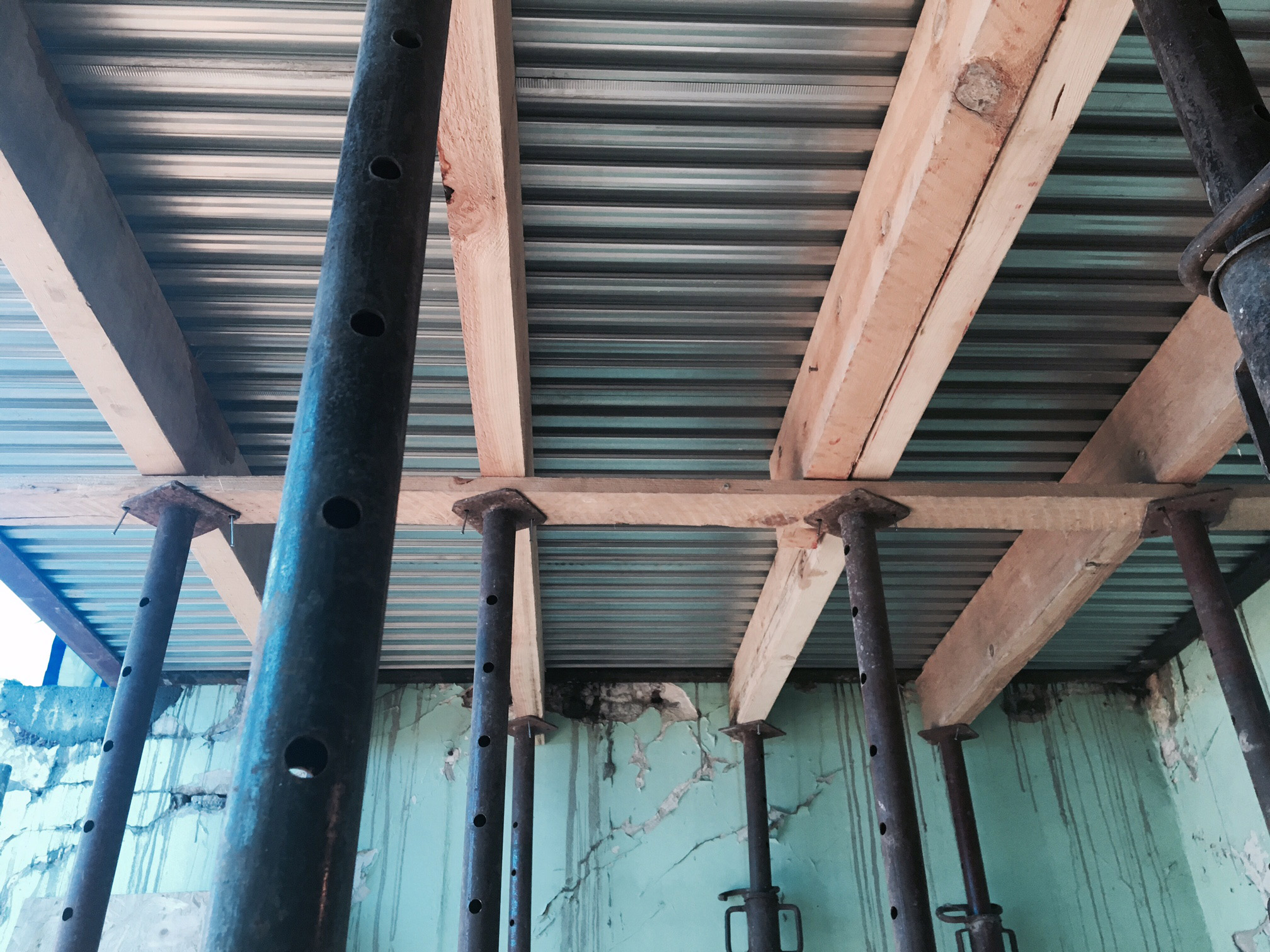 photo de chantier en cours : vue sur le plafond de l'atelier en plancher Lewis apparent, avec étançons de maintien