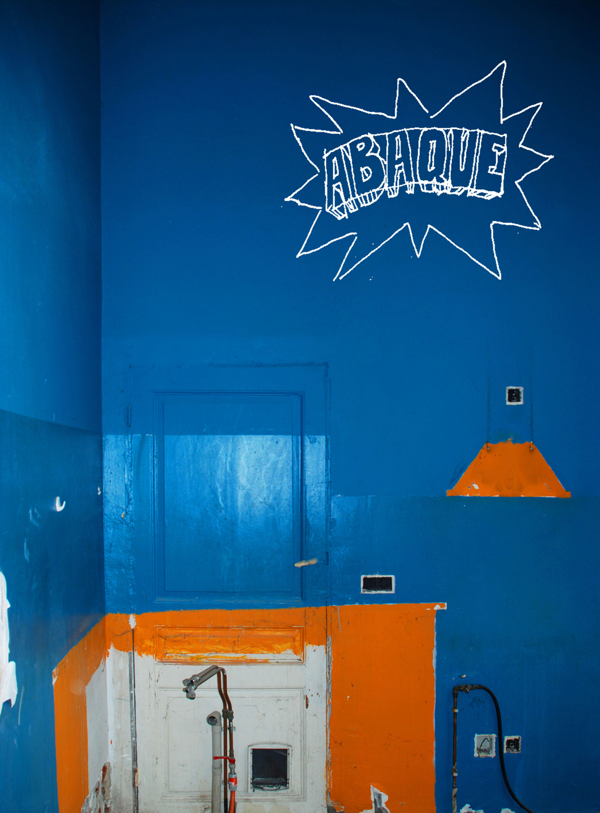 en cours de chantier : mur, ancienne porte et trace d'une hotte de cuisine sous peinture bleue, orange et blanche. Le logo d'Abaque est mis dans le coin droit