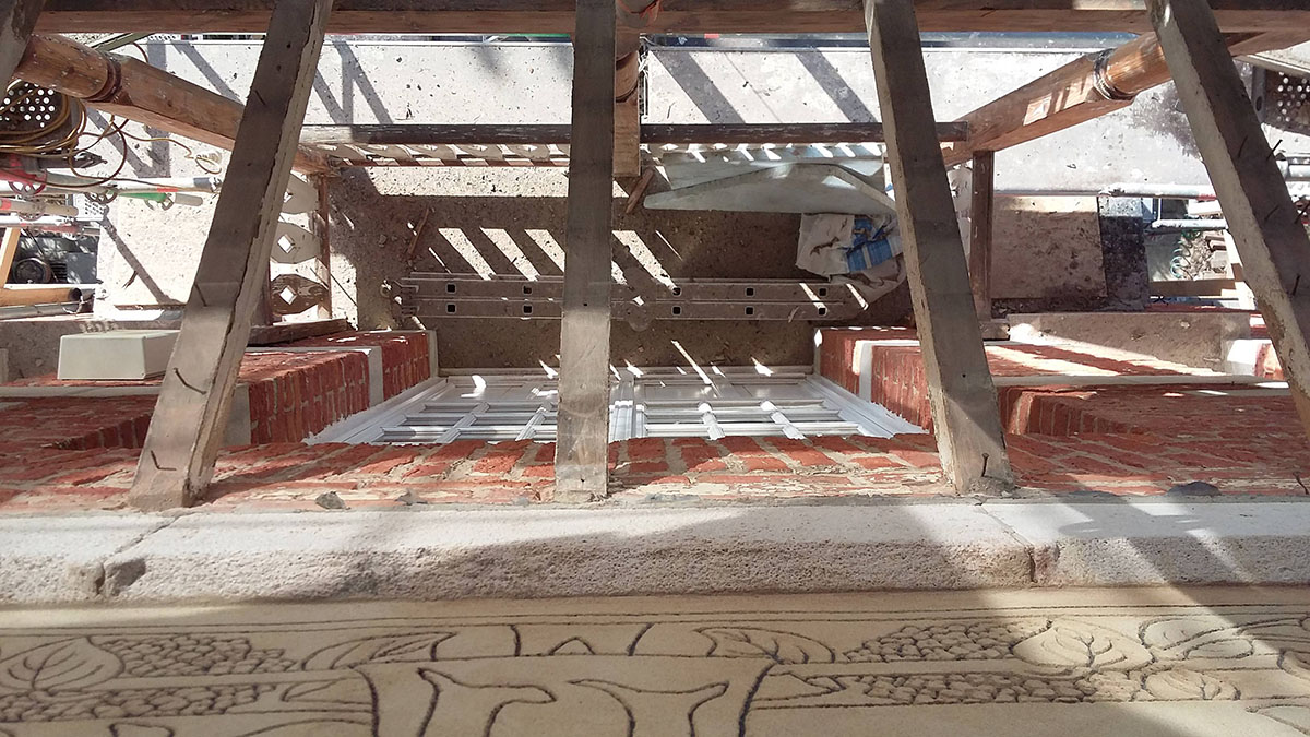 photo en cours de chantier : vue d'une partie du sgrafitte en cours et d'une des petites toitures partiellement démontée